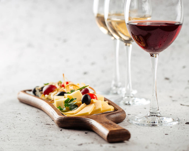 Glasses of wine and cheese appetizer board - 写真・画像
