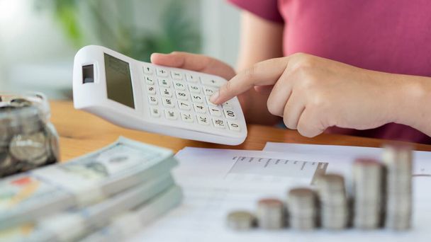 Koncepcja oszczędzania kobieta w czerwonym top obliczania miesięcznych wydatków i dochodów za pomocą kalkulatora. - Zdjęcie, obraz