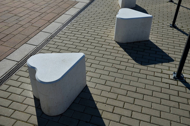 гладкі бетонні відливки розміру стільця. підходить як міський дизайнерський бар'єр для входу в пішохідну зону. форма кубиків цукру мокко. грати в карти символ канаста. білі серця на тротуарі
 - Фото, зображення