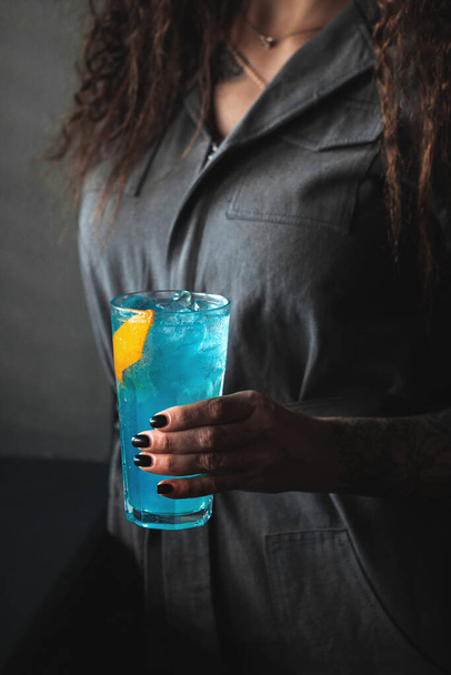 Femme tenant un cocktail bleu dans un highball avec de la glace - Photo, image