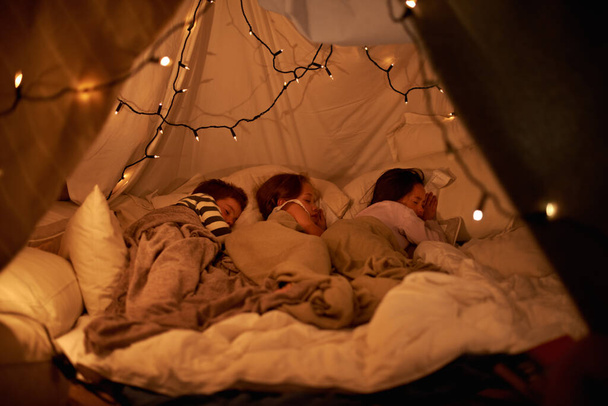 Dormir dans notre tente imaginaire. Prise de vue de trois jeunes enfants dormant dans une tente de couverture. - Photo, image