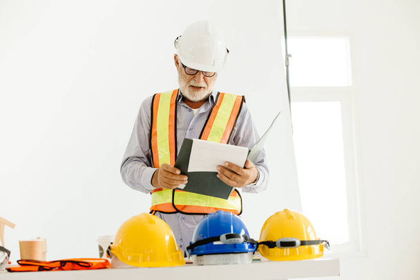Profesional ingeniero senior constructor viejo hombre trabajo mirando contrato detalle documento papel - Foto, imagen