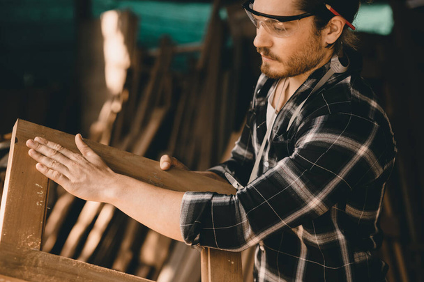 Плотники человек опытный деревообрабатывающий мебель. мастер по деревообработке мужчина смотрит на заготовки крупным планом с мелкими деталями. - Фото, изображение