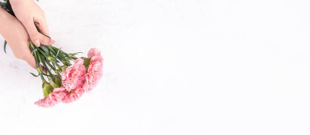 Mujer dando ramo de la elegancia floreciente bebé color rosa tiernos claveles aislados sobre fondo de mármol brillante, concepto de diseño de la decoración del día de las madres, vista superior, primer plano, espacio de copia
 - Foto, Imagen