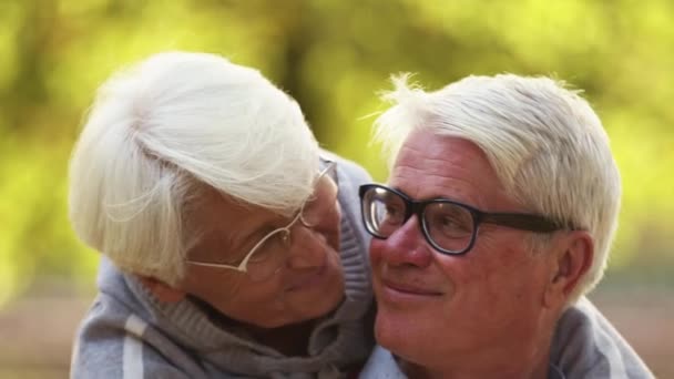 Happy senior Caucasian couple smiling to each other holding hands selective focus on faces look at the camera in the end  - Footage, Video