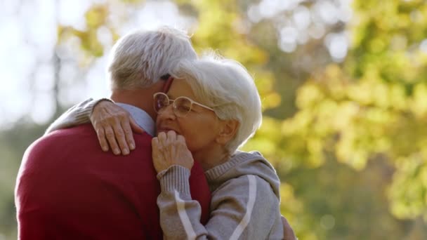 Ηλικιωμένοι Καυκάσιοι ζευγάρι αγκαλιάζει γυναίκα κινείται το χέρι της κατά μήκος των συζύγων της πίσω επιλεκτική εστίαση αντίγραφο χώρο  - Πλάνα, βίντεο