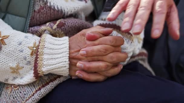 Az idős hölgy összekulcsolja az ujjait. A férje befedi őket a kezével. Idősebb pár együtt. Szelektív fókusz.  - Felvétel, videó