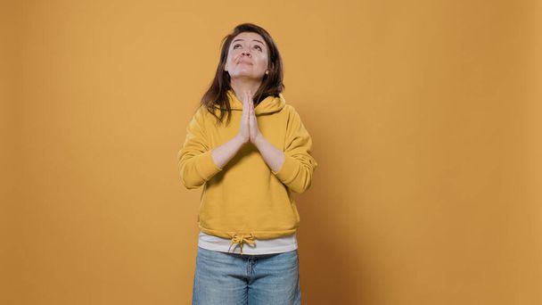 Lässige Frau, die sich Sorgen macht, betet und mit eng anliegenden Handflächen um Vergebung bittet - Foto, Bild