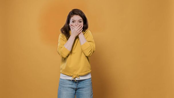 Portrait of shocked woman covering mouth with both hands surprised by unbelievable situation - Foto, Imagem