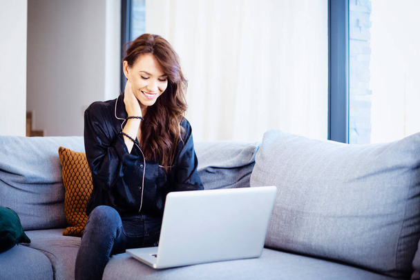Happy woman using her laptop while relaxing at home.  - 写真・画像