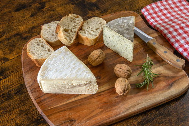 tomme de savoy and tomme with wild garlic on a wooden board with walnuts - Zdjęcie, obraz