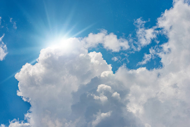 Прекрасне блакитне небо з білими кумульськими хмарами та сонячними променями (сонячними променями). Зйомка підсвічування
. - Фото, зображення