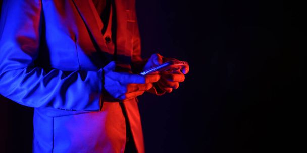 man in suit with smartphone  on dark background  - Foto, afbeelding