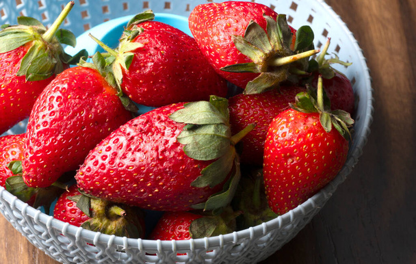 Heap of fresh strawberries in grey plastic bowl. Top view point. - Photo, Image
