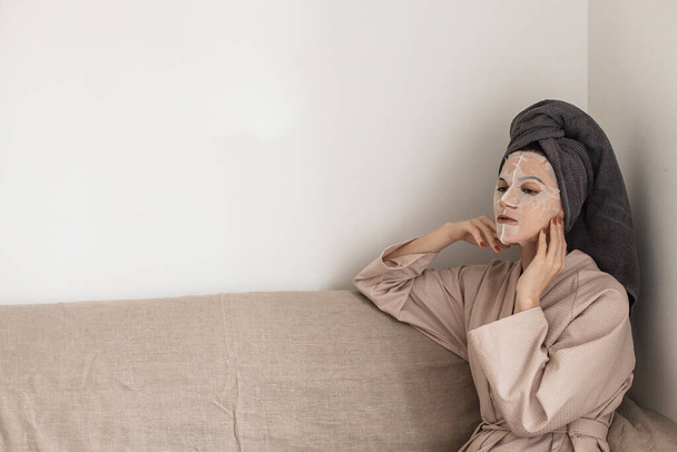 beautiful young woman in bathrobe lying on bed and looking at camera - Valokuva, kuva