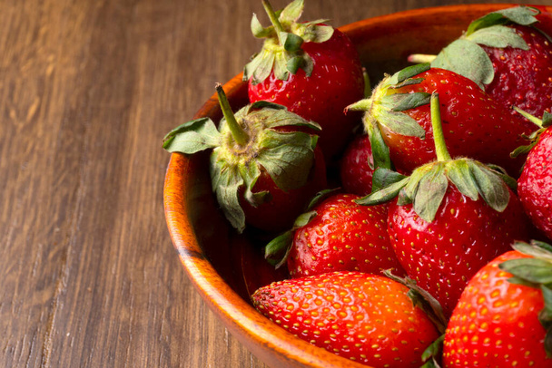 Vue de dessus des fraises juteuses dans un bol en bois sur une table rustique brune - Photo, image