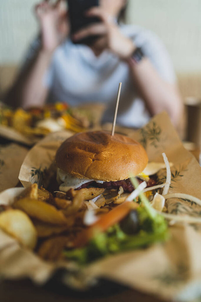 cropped view of female hands holding delicious burger with fresh vegetables - Fotografie, Obrázek