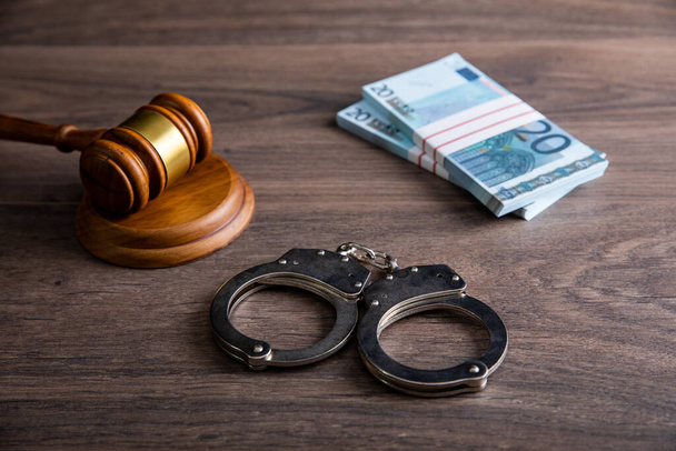 Gavel and handcuffs on the envelope with money - 写真・画像