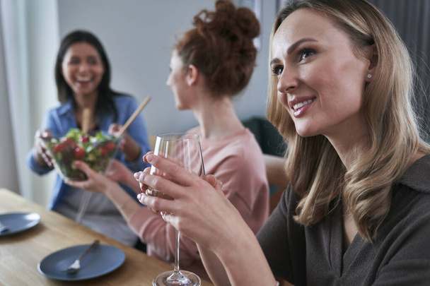 Üç beyaz kadın arkadaş sohbet ediyor ve evde şarap içiyor. - Fotoğraf, Görsel