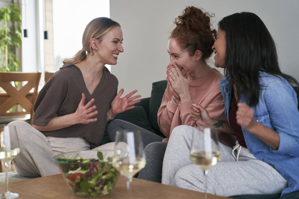 Three  female caucasian friends chatting and drinking wine at home - Photo, Image