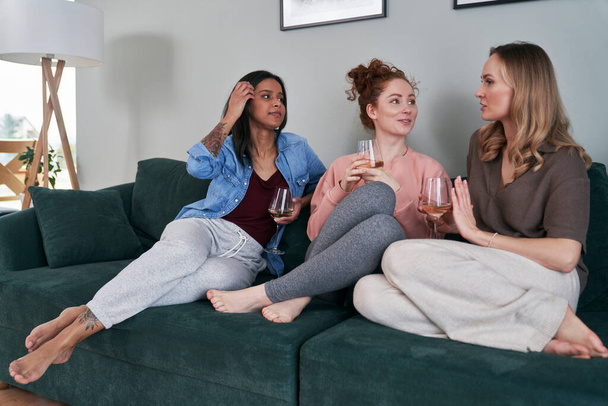 Tres amigas caucásicas charlando y bebiendo vino en casa - Foto, imagen