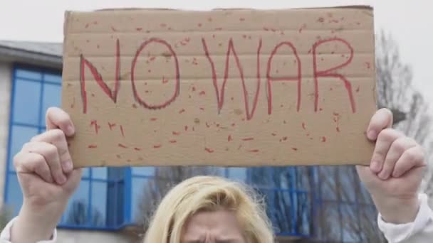 ウクライナの女性の手の詳細は、「戦争はありません」と言う記号を持つ青と黄色のウクライナの旗で、通りでは、ウクライナ・ロシア戦争に抗議します。. - 映像、動画