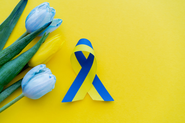 Vue du dessus des fleurs près du ruban bleu et jaune sur fond avec espace de copie - Photo, image