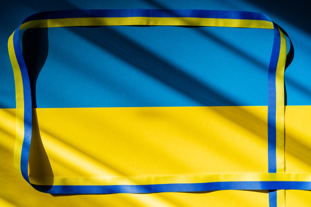 Κάτοψη πλαισίου από μπλε και κίτρινη κορδέλα σε ουκρανική σημαία με σκιά  - Φωτογραφία, εικόνα