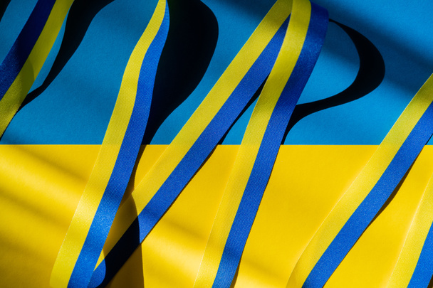 Top view of blue and yellow ribbon with shadow on ukrainian flag - Foto, Imagem