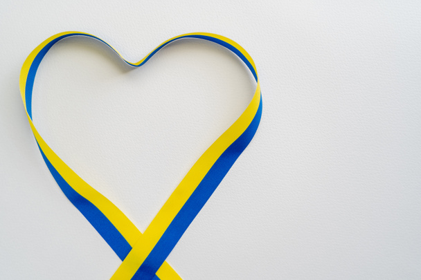Vista superior de la cinta azul y amarilla en forma de corazón sobre fondo blanco con espacio para copiar - Foto, Imagen