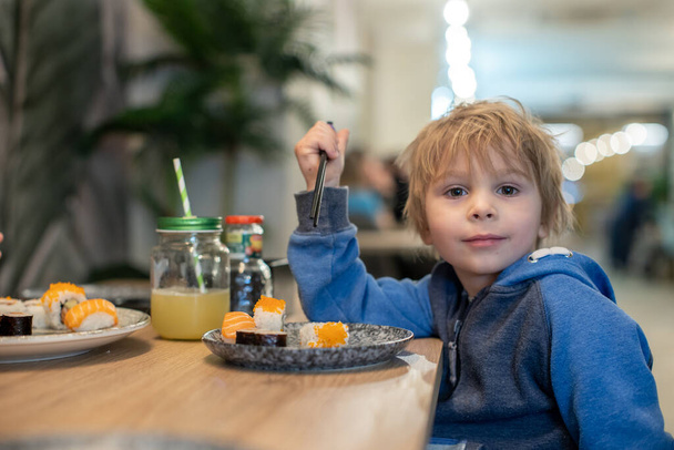 Child, eating japanese sushi and noodles with chopsticks in a restaurant, dinnertime - Valokuva, kuva