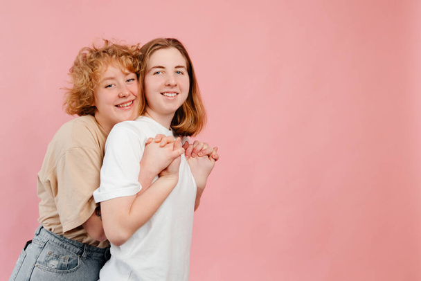 Mladý pár přítelkyň drží a baví izolované přes růžové pozadí. První koncept lásky - Fotografie, Obrázek