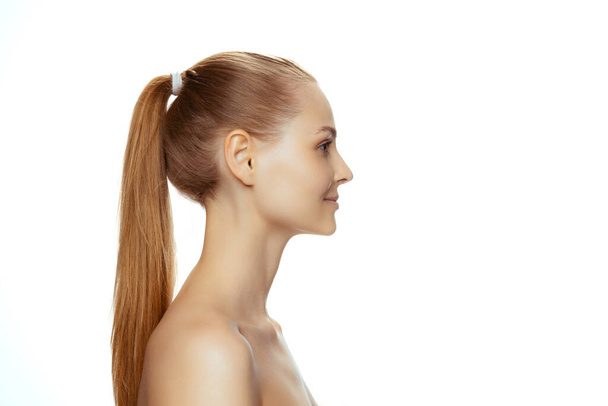 Portrait of young beautiful woman with ponytail posing isolated over white studio background. Side view - Photo, Image