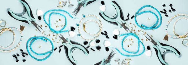 Tools and accessories for DIY jewelry in the workplace. Flat lay on blue cyan background. Creative flat lay, panoramic composition, extra wide banner, top view. DIY craft hobby, homemade business. - Photo, Image