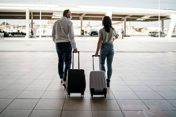 Um casal de amigos com bagagem usando máscaras protetoras deixando o aeroporto - Foto, Imagem