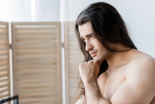 pensive shirtless man with long hair looking away - 写真・画像