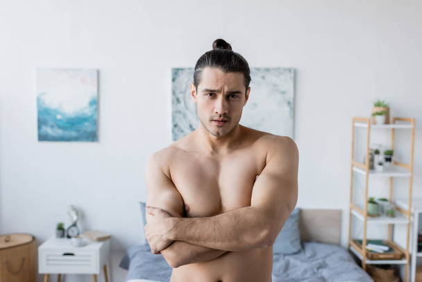 shirtless man with long hair standing with crossed arms and looking at camera - Fotó, kép