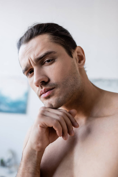 serious and shirtless man looking at camera at home - Fotografie, Obrázek