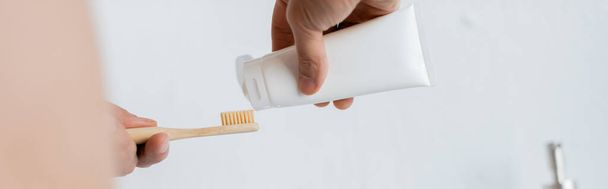 καλλιεργημένη άποψη του ανθρώπου συμπίεση οδοντόκρεμα στην οδοντόβουρτσα στο μπάνιο, πανό - Φωτογραφία, εικόνα