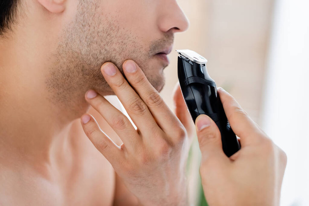 cropped view of man shaving with electric razor - Foto, Imagen