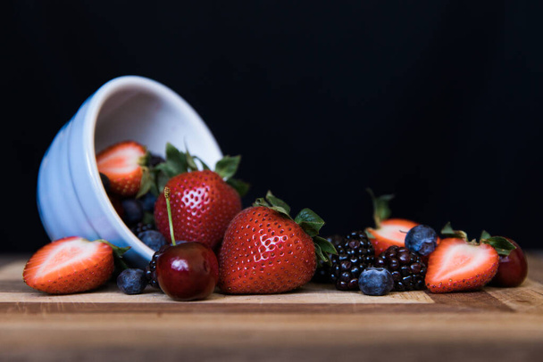 fresh berries in a bowl on a black background - Foto, afbeelding
