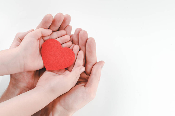 Isän ja pojan kädet punaisella sydämellä valkoisella pohjalla, sydänsairausvakuutus, perhepäivä, maailman sydänpäivä - Valokuva, kuva
