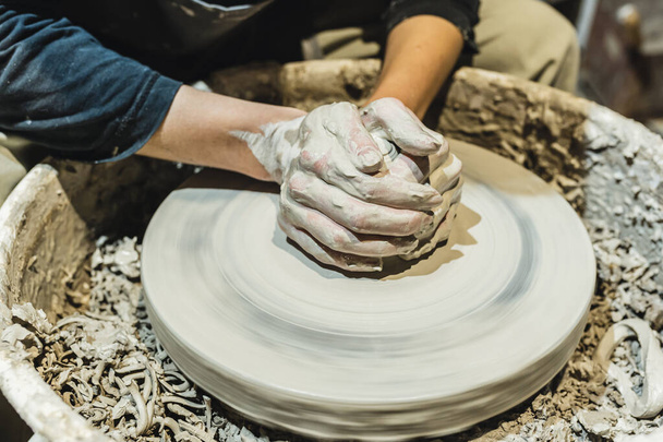 Potterovy ženské ruce, zašpiněné hlínou, tvoří hliněnou hromádku na hrnčířském kole. Řemeslná jílovitá keramika, hobby lidové umění. Potterovy ruce zblízka, na hrnčířském kole, v jílu, výroba keramiky - Fotografie, Obrázek