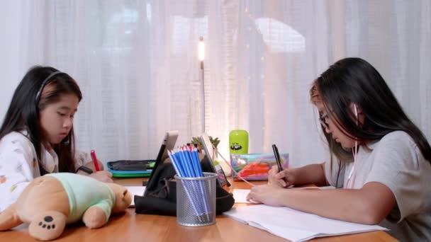 4Kアジアの子供たちは、自宅で遠隔学習デジタルタブレットを使用しています。家庭教育, covid19中の社会的距離...兄弟は家でオンラインタブレットの研究を使用してテーブルの周りに座って - 映像、動画