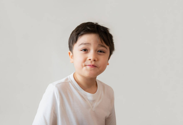 Portré aranyos boldog fiatal fiú fehér pólóban felnézett meglepett arccal, Fejlövés pozitív gyerek mosolygós arccal és vicces arcot. A gyermeknapok fogalma - Fotó, kép