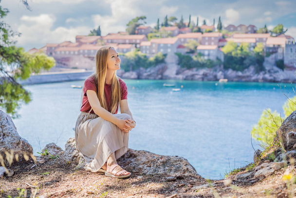 Woman tourist on background of beautiful view of the island of St. Stephen, Sveti Stefan on the Budva Riviera, Budva, Montenegro. Travel to Montenegro concept - Zdjęcie, obraz