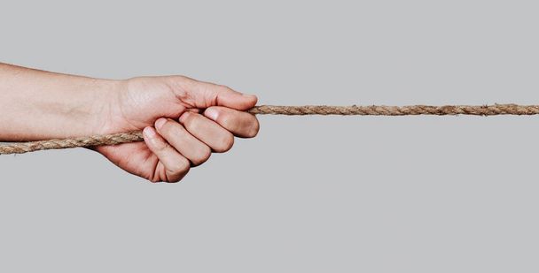 closeup of a caucasian man pulling a rope against a pale gray background, in a panoramic format to use as web banner or header - Photo, Image