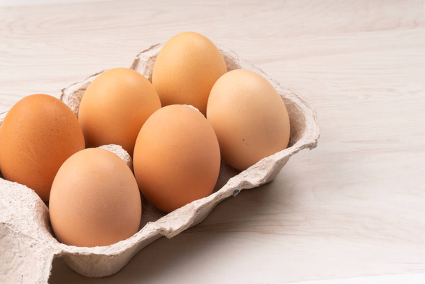 Six chicken eggs in cardboard box, closeup shot  - 写真・画像