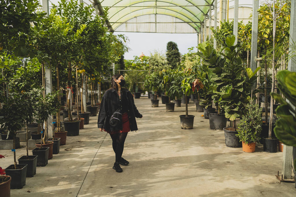 young woman in a protective mask and gloves working in the greenhouse - Foto, imagen
