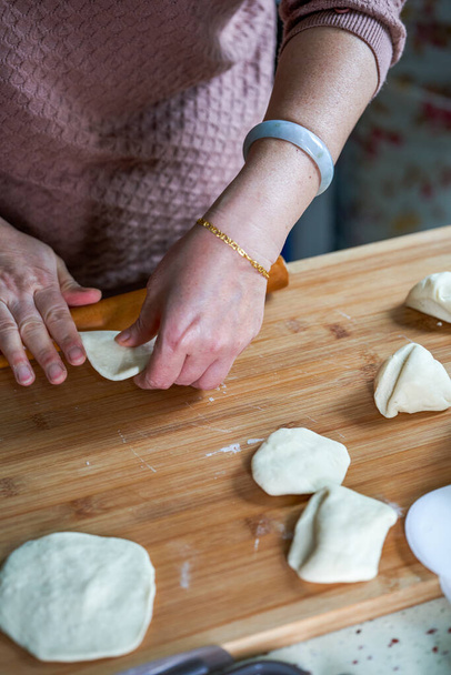 Un chef en una cocina china está haciendo pieles de pan con un rodillo - Foto, Imagen